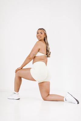 Kneeling lunge in a cream set, movement in studio